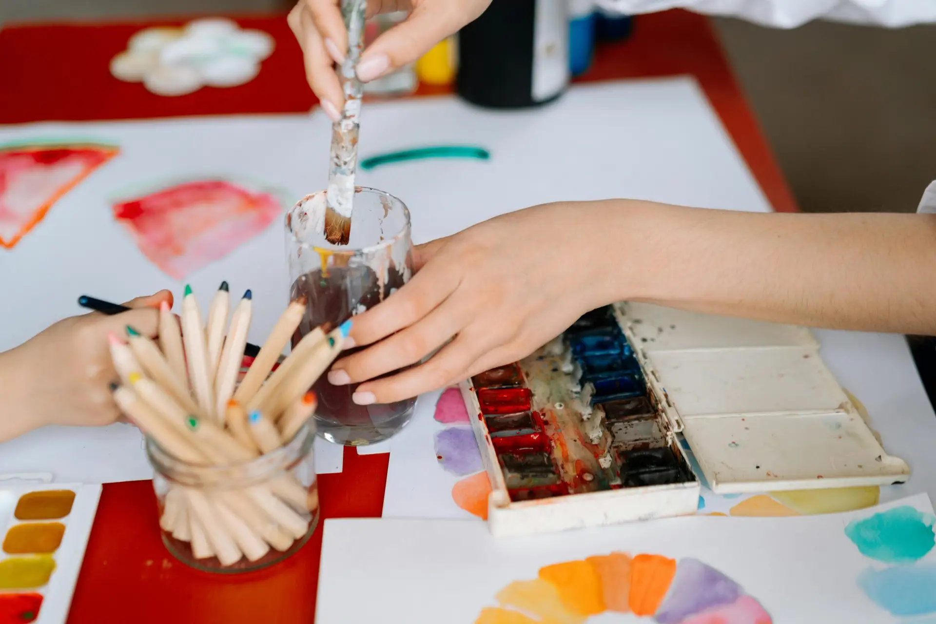 Hands interacting with watercolors and brushes during a creative art activity.
